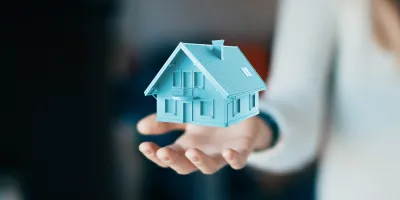 Une femme qui a au dessus de sa main droite une maison bleue en lévitation